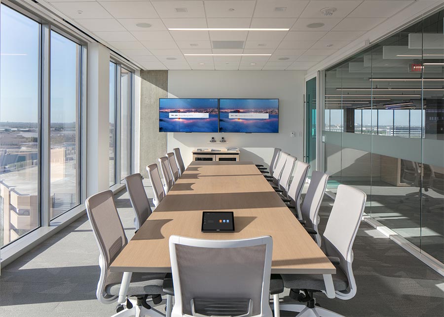 Bright conference room with long table, modern chairs, and screens