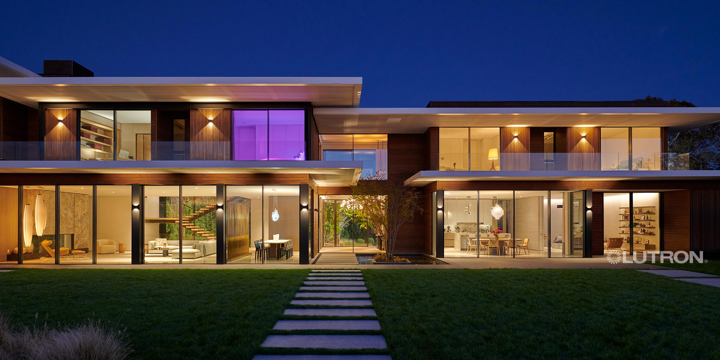 Modern house exterior at night with glass walls and warm lights