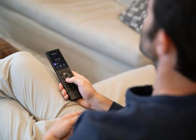 Man holding a smart remote while relaxing on a couch
